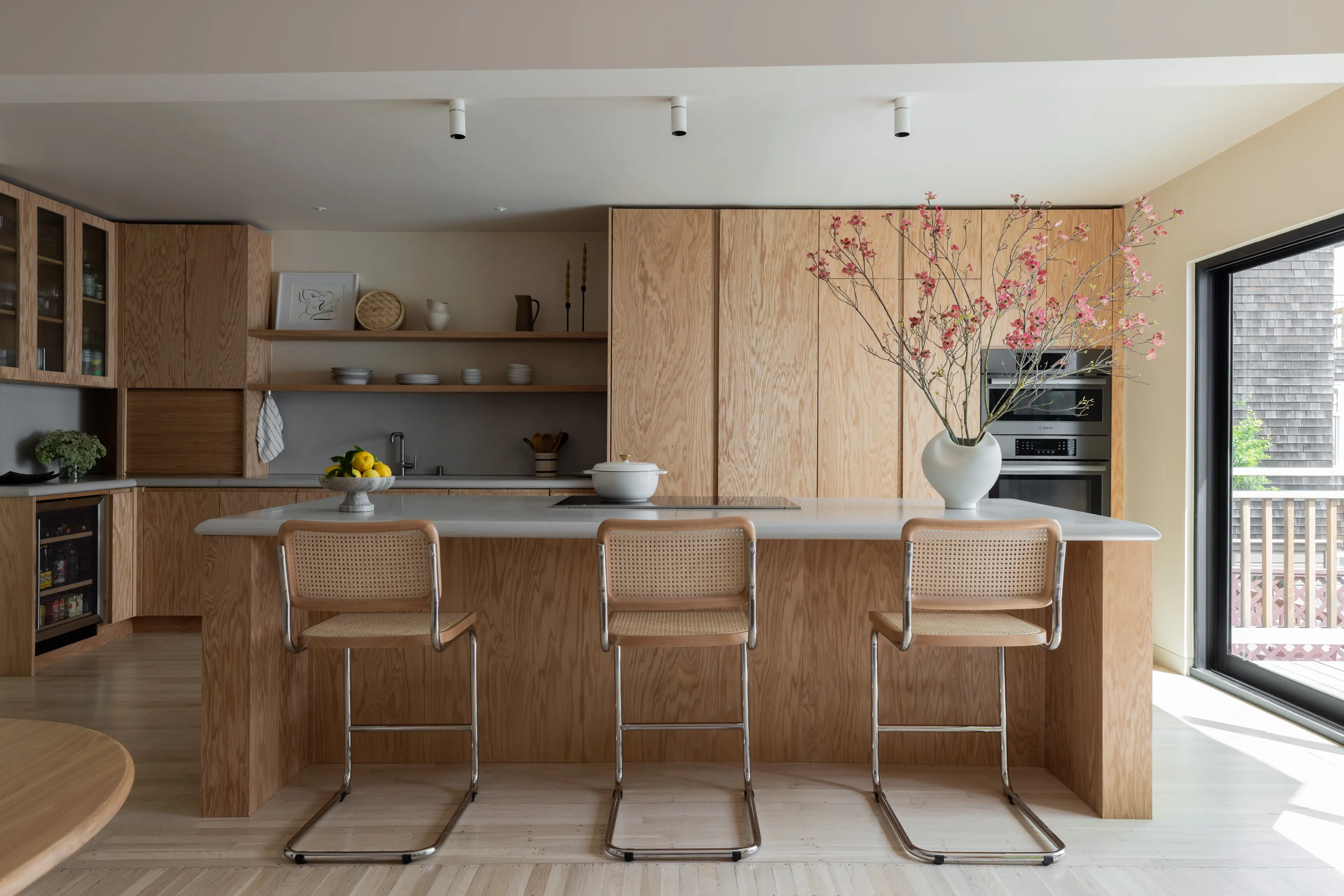 Kitchen with custom red oak cabinetry, concrete-topped island, and Cesca cane counter stools in Parnassus Heights home designed by Studio VAE, San Francisco interior designer.