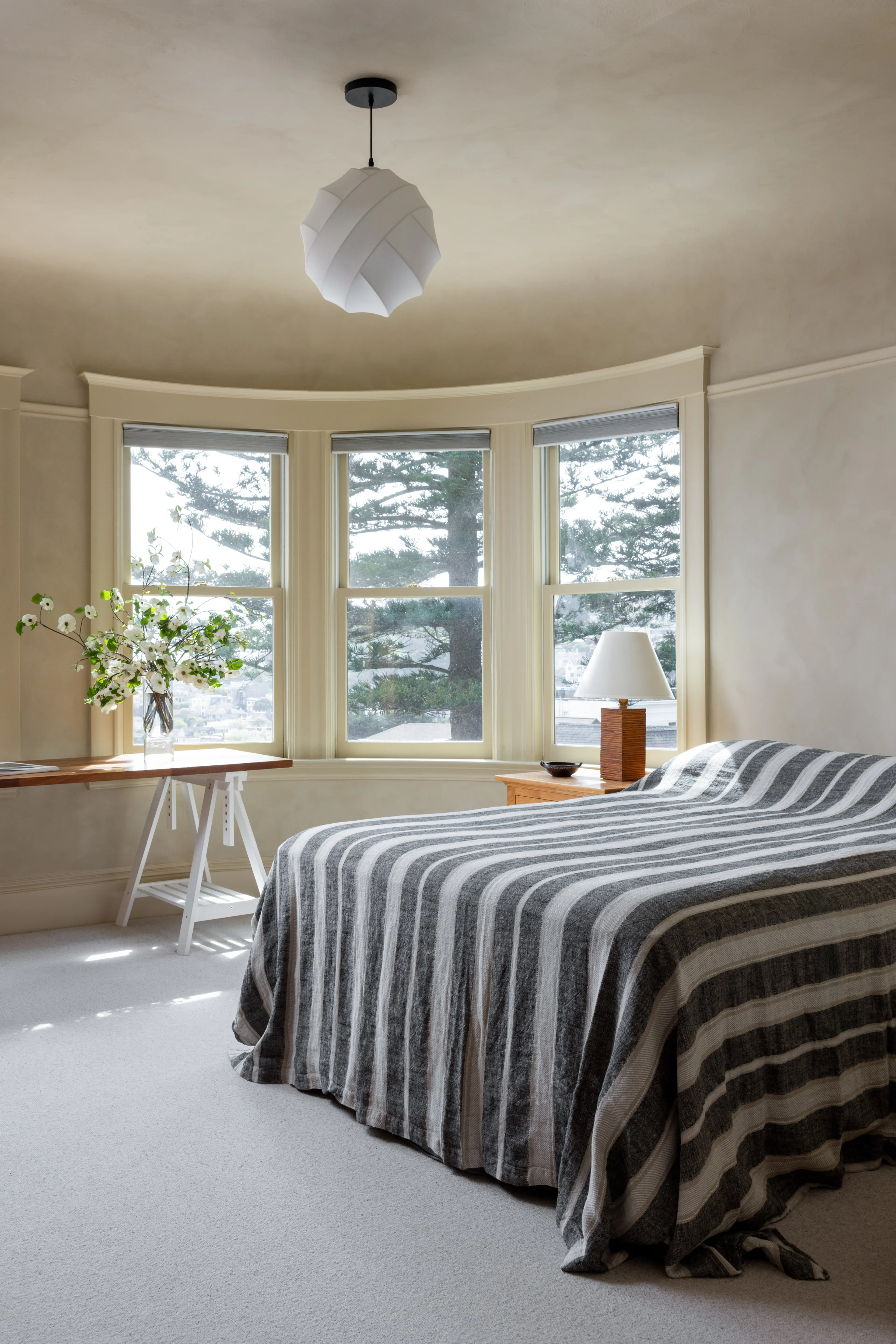 Guest bedroom in a Parnassus Heights home, with paper pendant light, lime washed walls and a striped bedspread